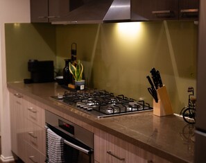 A kitchen with a gas stove, wooden cabinets, a stainless steel range hood, and a knife block. - Modern Cozy Retreat, Park, Mall! (Berwick)
