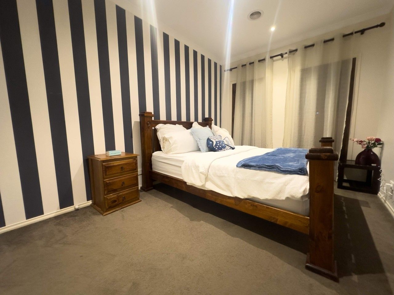 Ein Schlafzimmer mit einem hölzernen Bett, einem Nachttisch und einer Kommode.