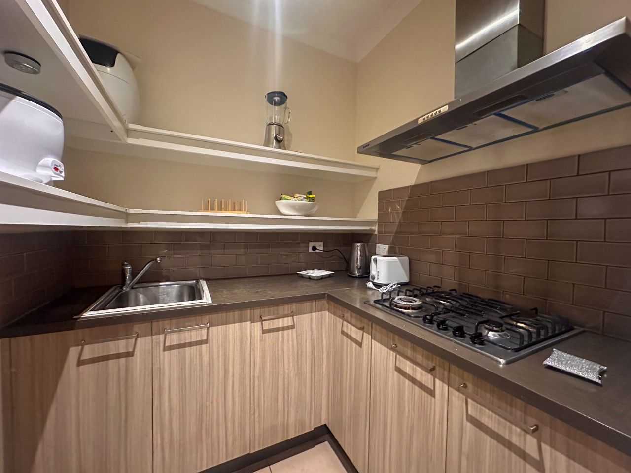 A modern kitchen with a gas stove, a sink, and a toaster.
