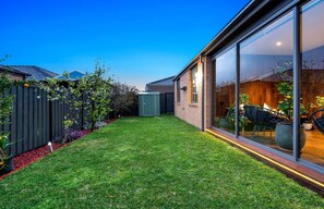 A modern residential property with a well-maintained lawn, a wooden fence, and a glass-enclosed patio area. - Modern Cozy Retreat, Park, Mall! (Berwick)