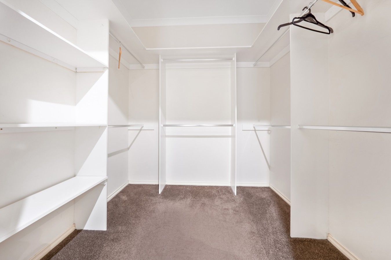 A walk-in closet with open shelves and a hanging rod.