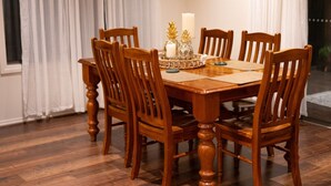 A wooden dining table with six chairs, a candle, and decorative items on the table.