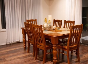 A wooden dining table with six chairs, a candle, and decorative items on the table. - Modern Cozy Retreat, Park, Mall! (Berwick)