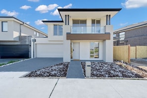 A modern two-story house with a garage, a front porch, and a small garden area. - Modern Cozy Retreat, Park, Mall! (Berwick)