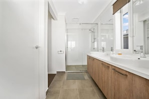A modern bathroom with a large mirror, a shower, and a vanity with a sink. - Modern Cozy Retreat, Park, Mall! (Berwick)