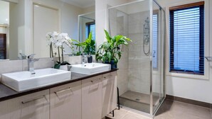 A modern bathroom with a glass-enclosed shower, two sinks, and potted plants. - Modern Cozy Retreat, Park, Mall! (Berwick)