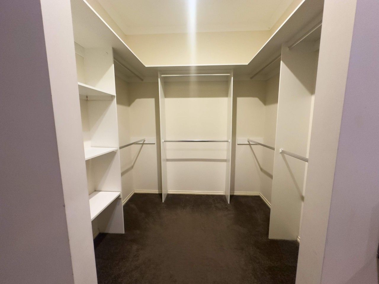 A walk-in closet with open shelving and a central hanging rod.