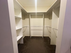 Un armario de vestidor con repisas abiertas y una barra central para colgar ropa.