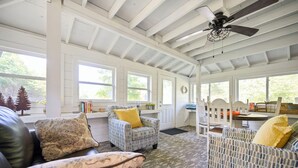 A spacious room with a high ceiling, large windows, and a ceiling fan. There are two patterned armchairs and a sofa with cushions. - Mt.Fork Hideaway, Pickleball, Hot Tub, 4 private acres (Broken Bow)