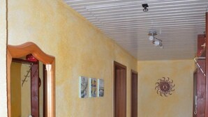 A hallway with a tiled floor, wooden doors, a mirror, and wall-mounted pictures.