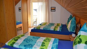 A bedroom with two beds, a wooden ceiling, and a view of the outside.