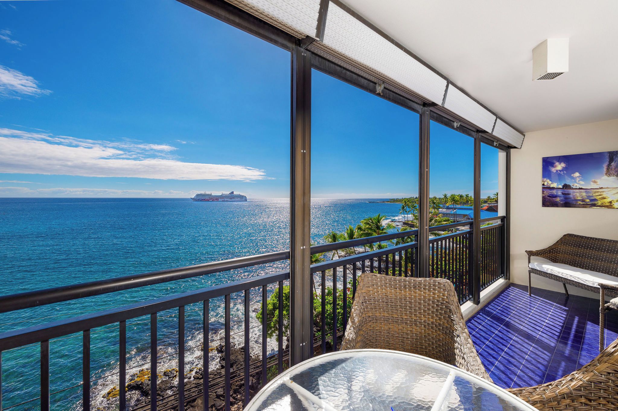 A balcony with a clear view of the ocean and a cruise ship in the distance.
