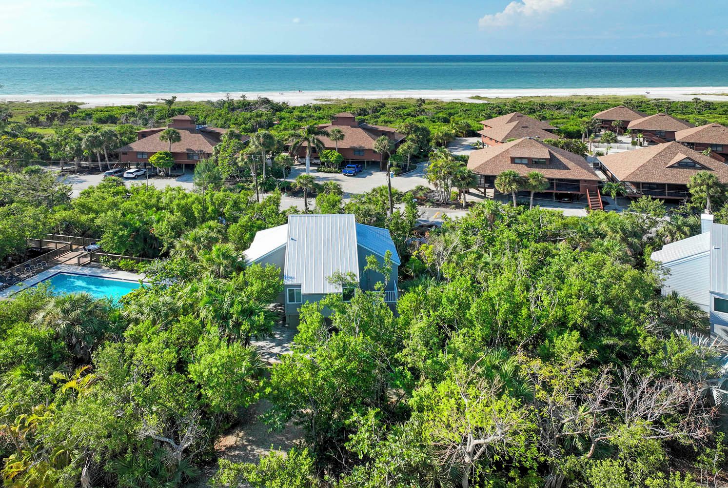 A resort with multiple bungalow-style buildings, a swimming pool, and a beach view.