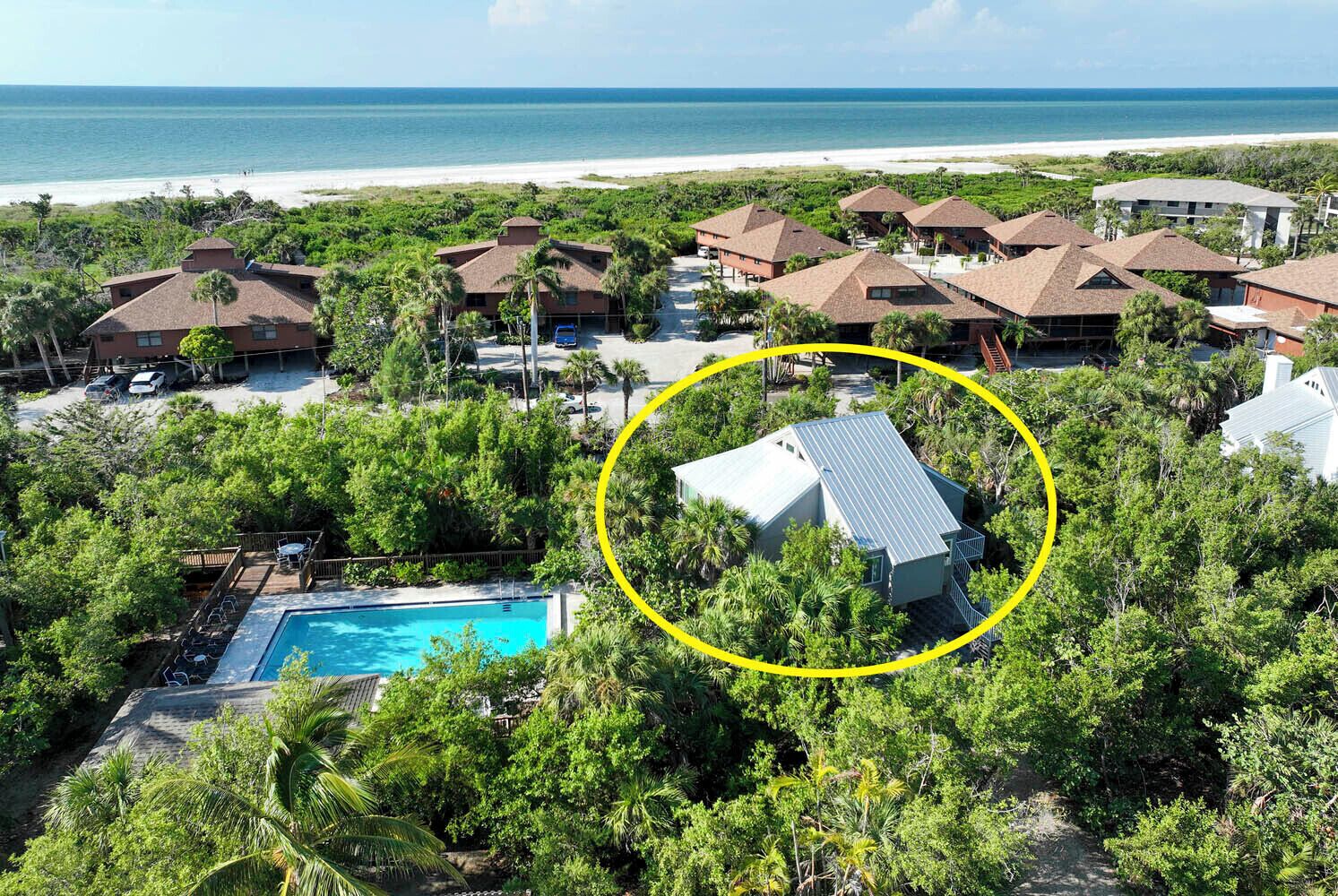 A resort with multiple buildings, a swimming pool, and a beach view.