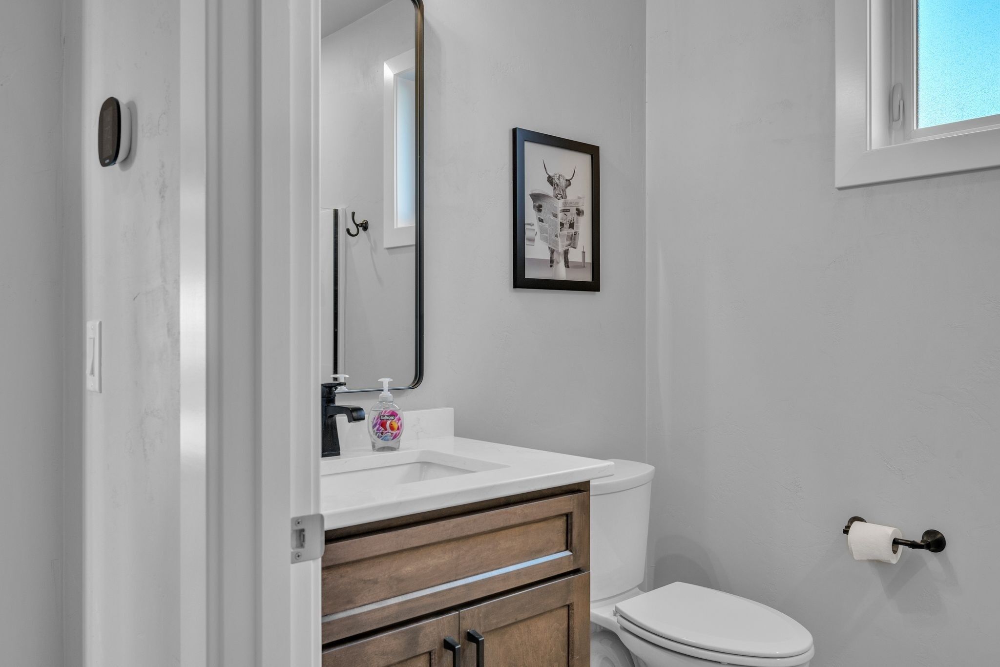 A bathroom with a white sink, wooden cabinet, and a toilet.