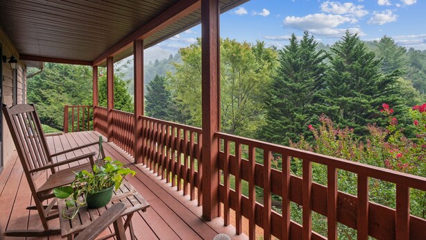 A wooden deck with a railing, a bench, and a table with a potted plant. - Whispering Pines - Spectacular Views & Hot Tub 3 Bedroom Home (Burnsville)