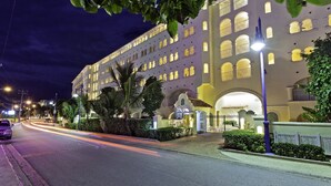 A large, multi-story hotel with a symmetrical facade, multiple balconies, and a well-lit entrance.
