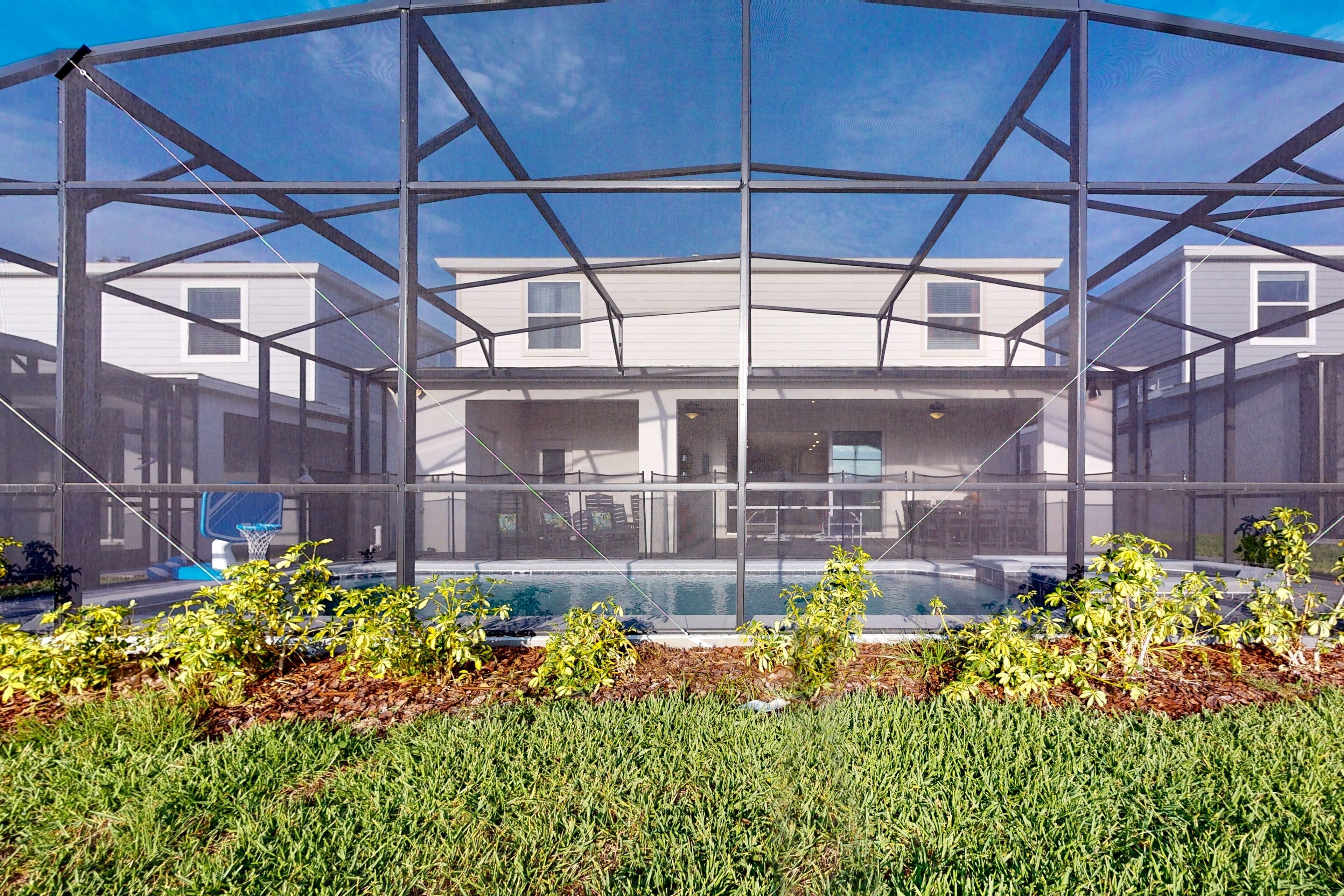 A modern building with a glass facade, a pool, and a well-maintained lawn.