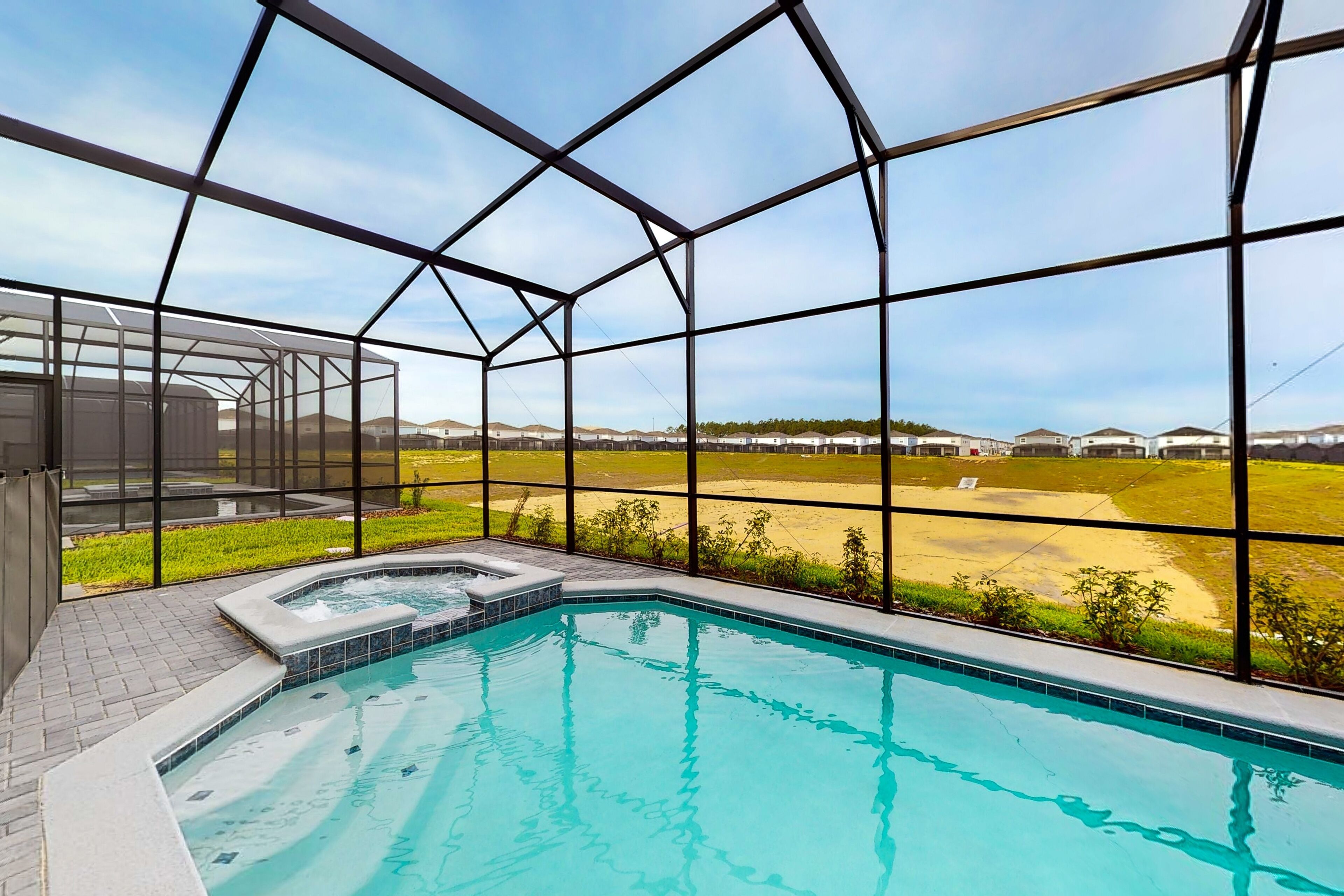 A swimming pool with a view of a golf course through large windows.