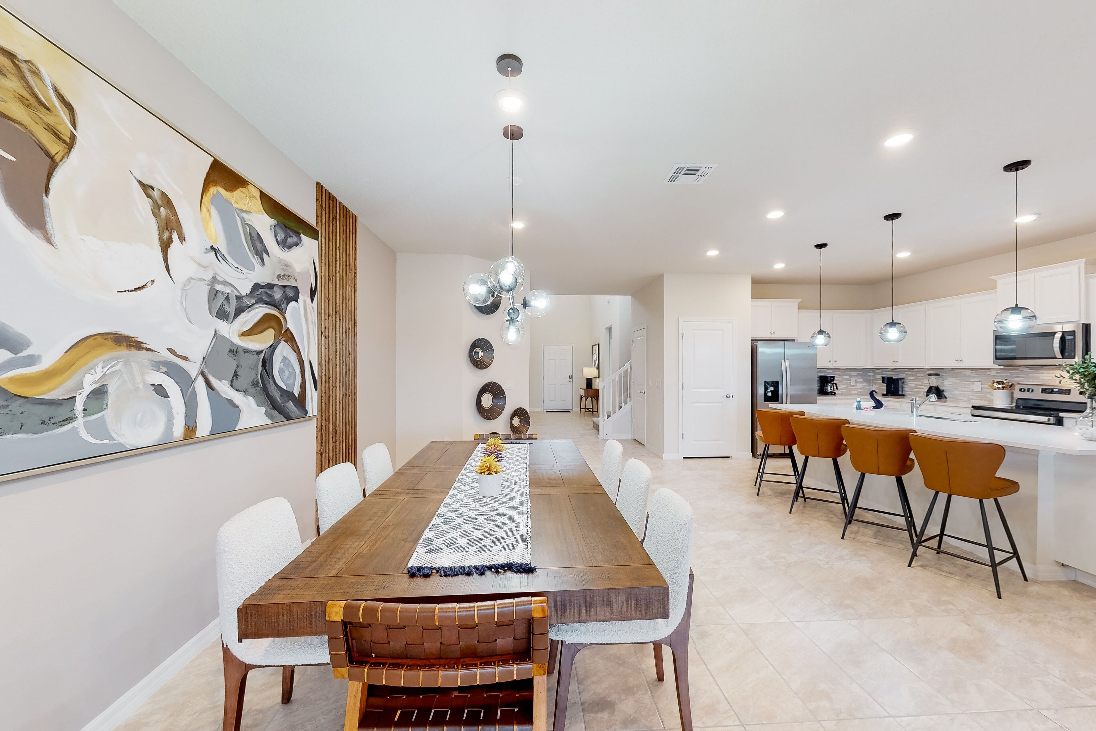 Una cocina moderna con gabinetes blancos, una isla central e iluminación colgante.