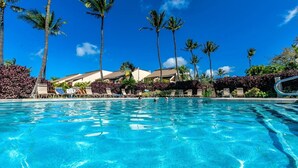 A clear blue pool with lounge chairs and palm trees. - Maui Kamaole L107 1 Bedroom Condo (Kihei)