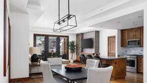 A modern kitchen with a central island, built-in appliances, and a dining area with a black table and white chairs. - Luxury 4bdr Residence Steps From Heavenly Village 4 Bedroom Condo (South Lake Tahoe)