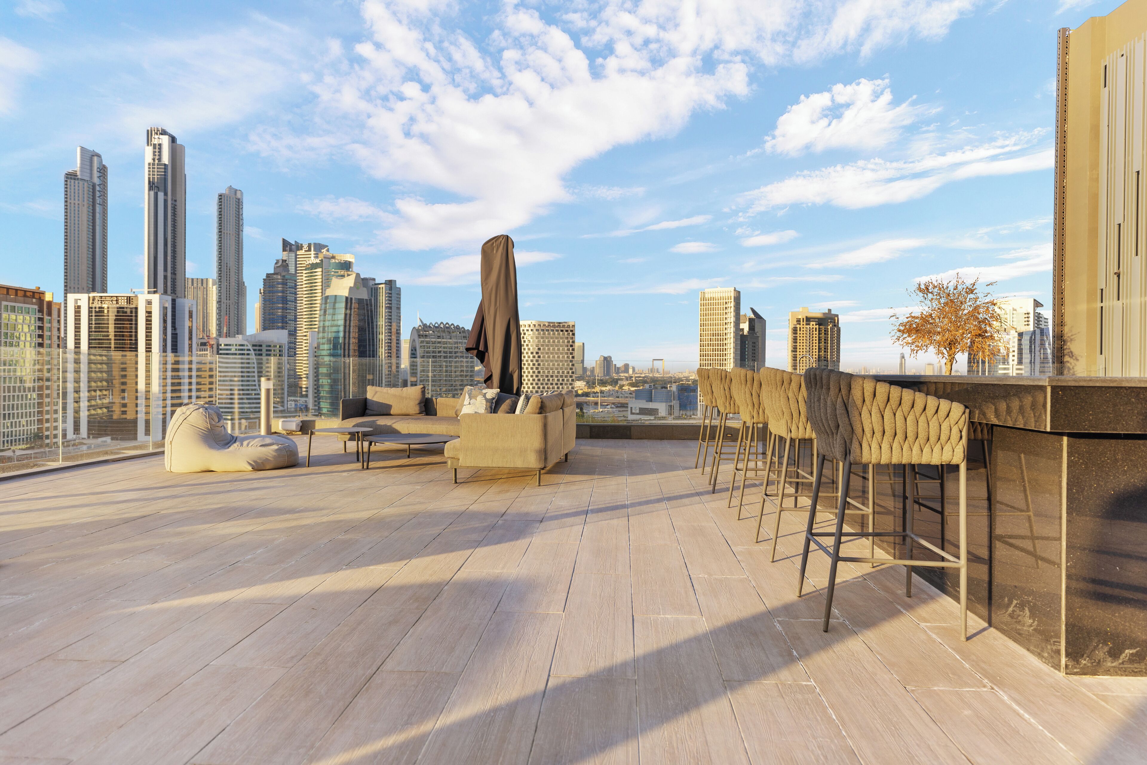 A rooftop terrace with a city skyline view, modern seating, and a bar area.