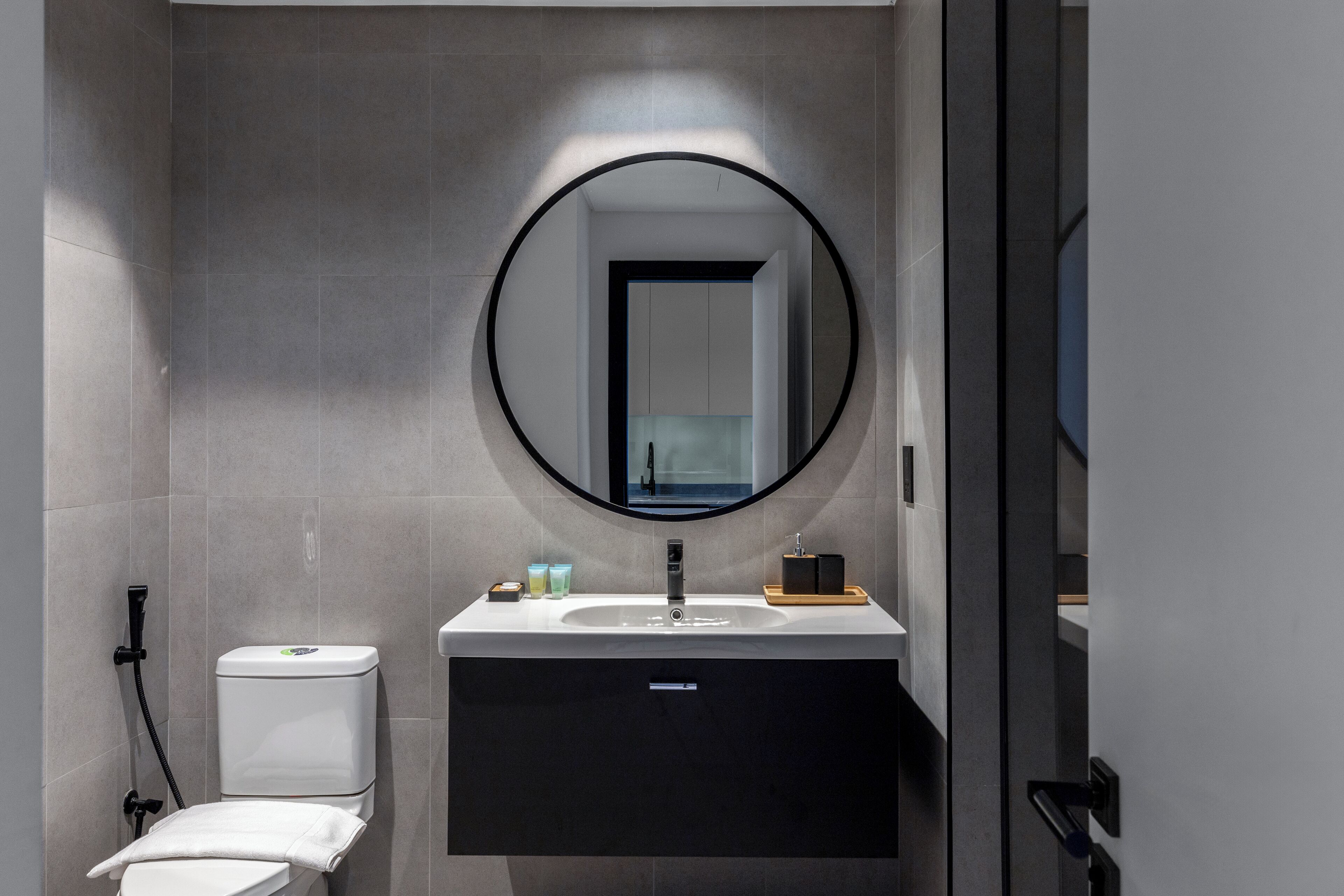 A modern bathroom with a toilet, sink, and mirror.