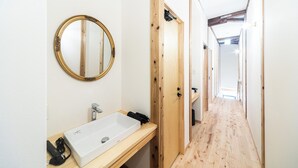 A bathroom with a white sink, a gold-framed mirror, and wooden doors. - Fukuoka Guesthouse CAMP (Fukuoka)