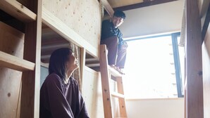 A wooden interior with a person on a ladder and another person standing below. - Fukuoka Guesthouse CAMP (Fukuoka)