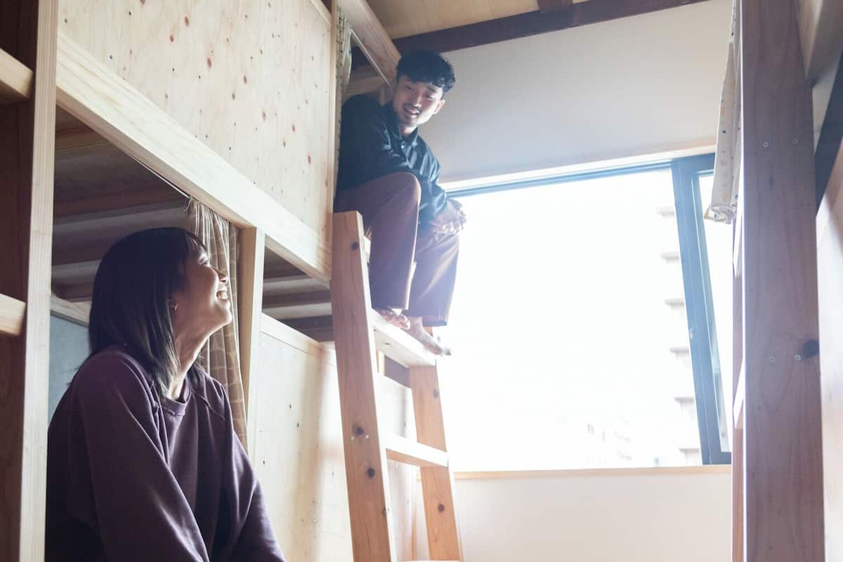 A wooden interior with a person on a ladder and another person standing below.