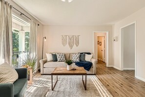 Una sala de estar con sofá, mesa de centro y vista al exterior.