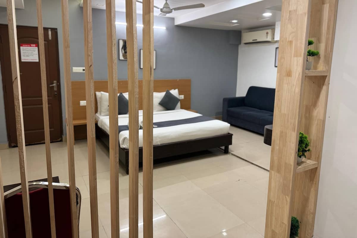 A hotel room with a bed, a sofa, a wooden partition, and a ceiling fan.