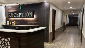 A reception area with a dark wood reception desk, a sign reading "RECEPTION", and a hallway with a light-colored tiled floor. - Bommarillu Residency (Hyderabad)