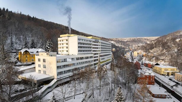 Um hotel com vários andares e design moderno, situado numa região montanhosa coberta de neve.