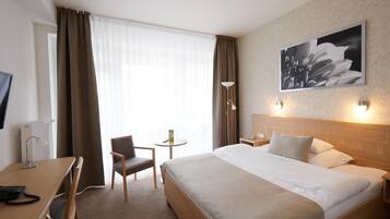 Ein Hotelzimmer mit Bett, Schreibtisch, Stuhl, Lampe und einem Bild an der Wand.