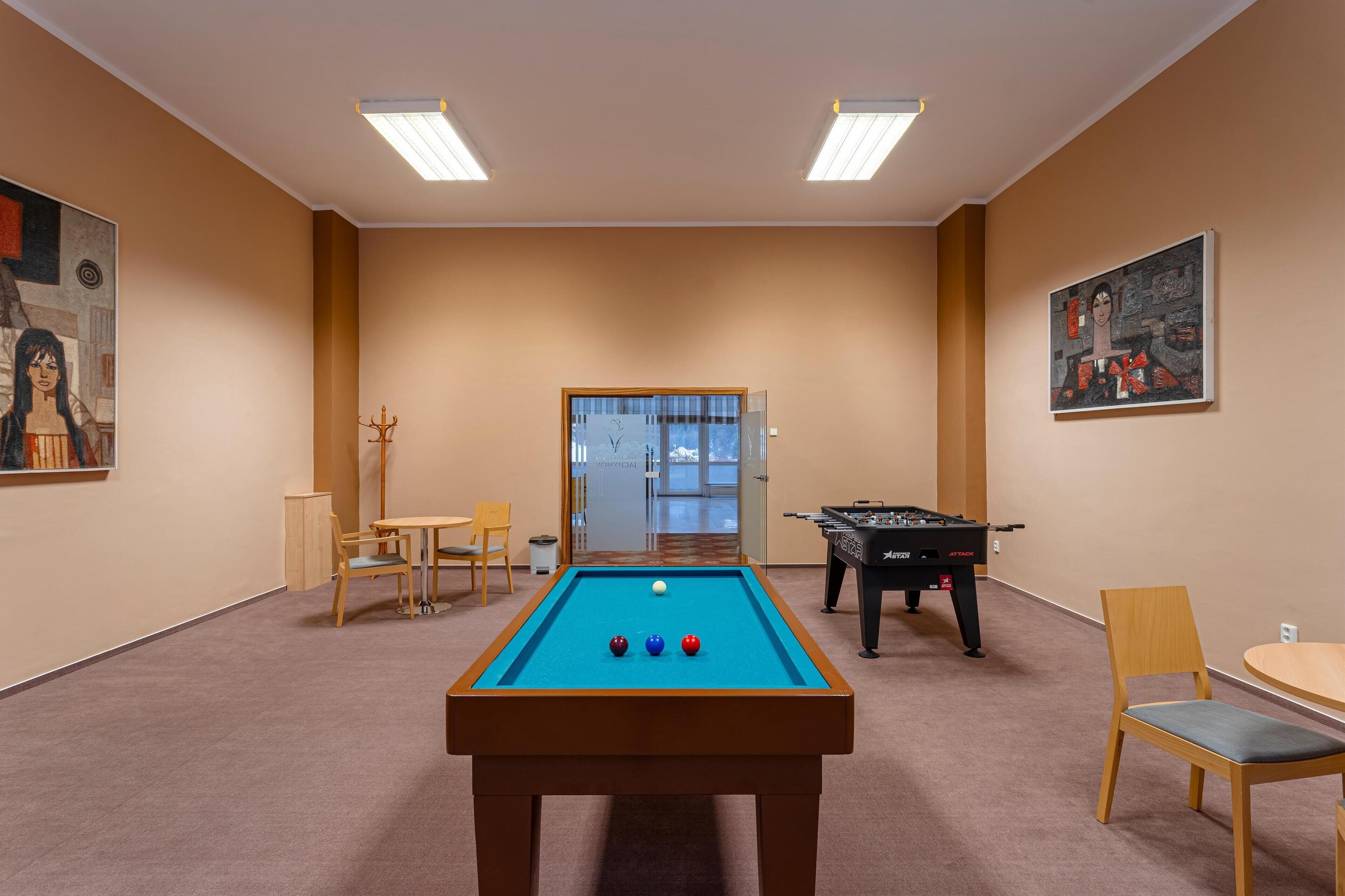 A pool table with balls, a foosball table, and a door leading to a hallway.