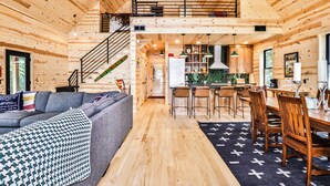 Ein gemütliches Blockhaus-Interieur mit Schlafzimmer im Zwischengeschoss, Essbereich und Küche.