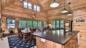 Ein Holzblockhaus-Interieur mit Essbereich, Küche und großen Fenstern.