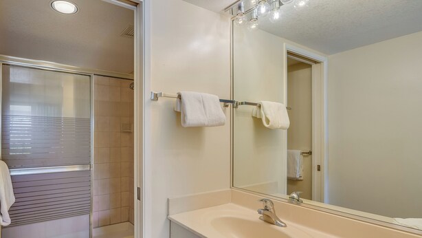 Une salle de bain moderne avec une douche à parois de verre, un grand miroir et un lavabo de couleur beige.