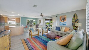 A spacious living area with a sofa, ottoman, and chairs, a kitchen with wooden cabinets, and a dining area with a table and chairs.