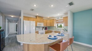 A modern kitchen with a large island, wooden cabinets, and stainless steel appliances.
