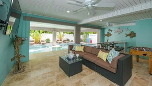 A spacious outdoor living area with a pool, comfortable seating, and a foosball table.