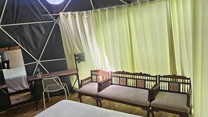 Un alloggio in tenda con un letto, due divani di legno, un tavolo e una sedia.