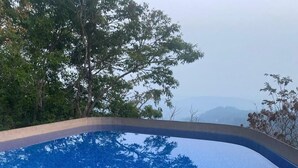 Una piscina con piastrelle blu e vista su alberi e montagne sullo sfondo.