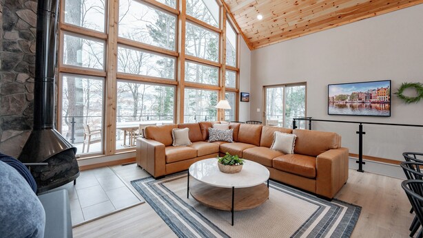 A spacious living room with a large sectional sofa, a round coffee table, and a stone fireplace.