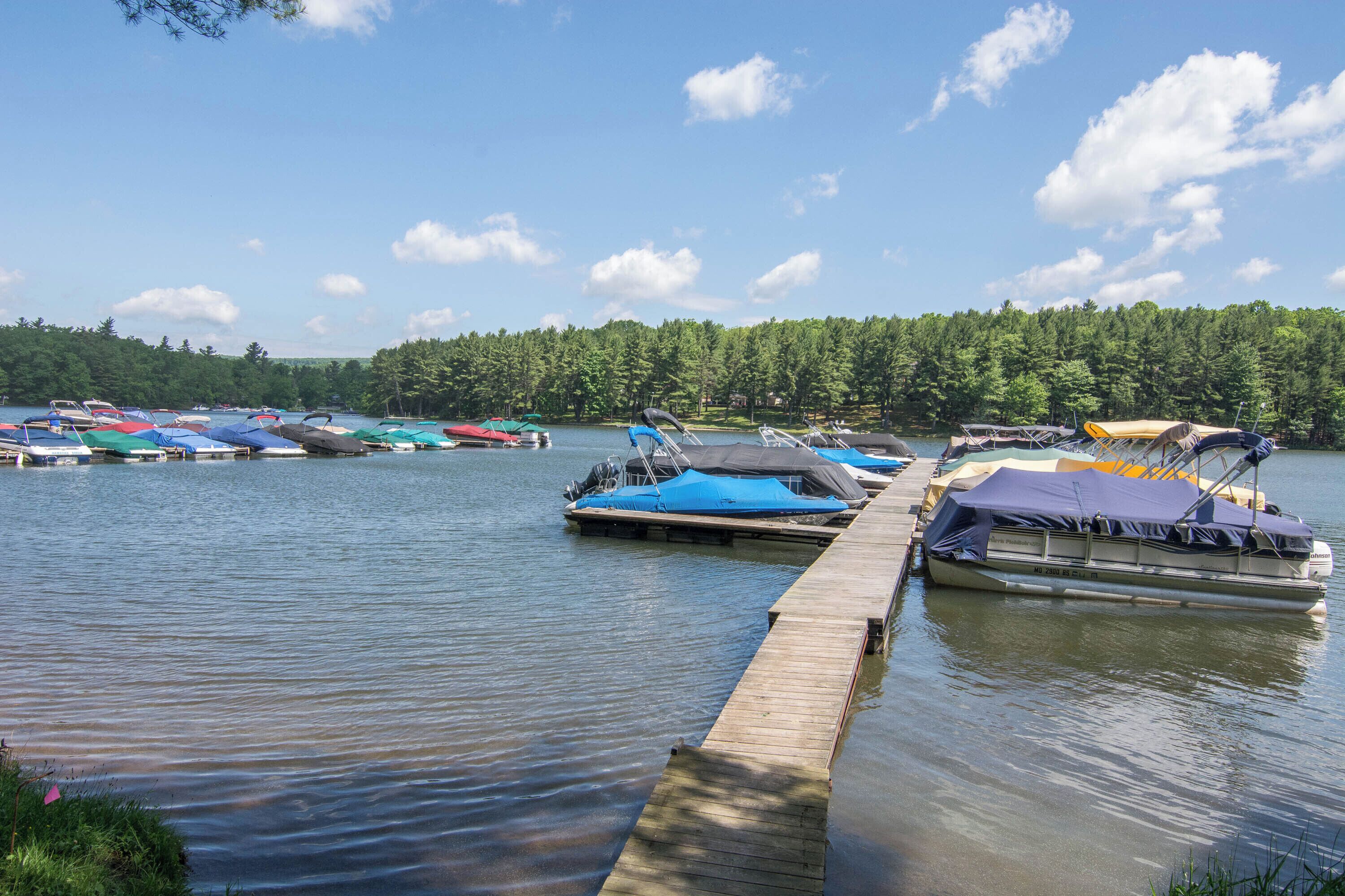 Ein ruhiger See mit mehreren Booten, die an einem hölzernen Steg festgemacht sind.