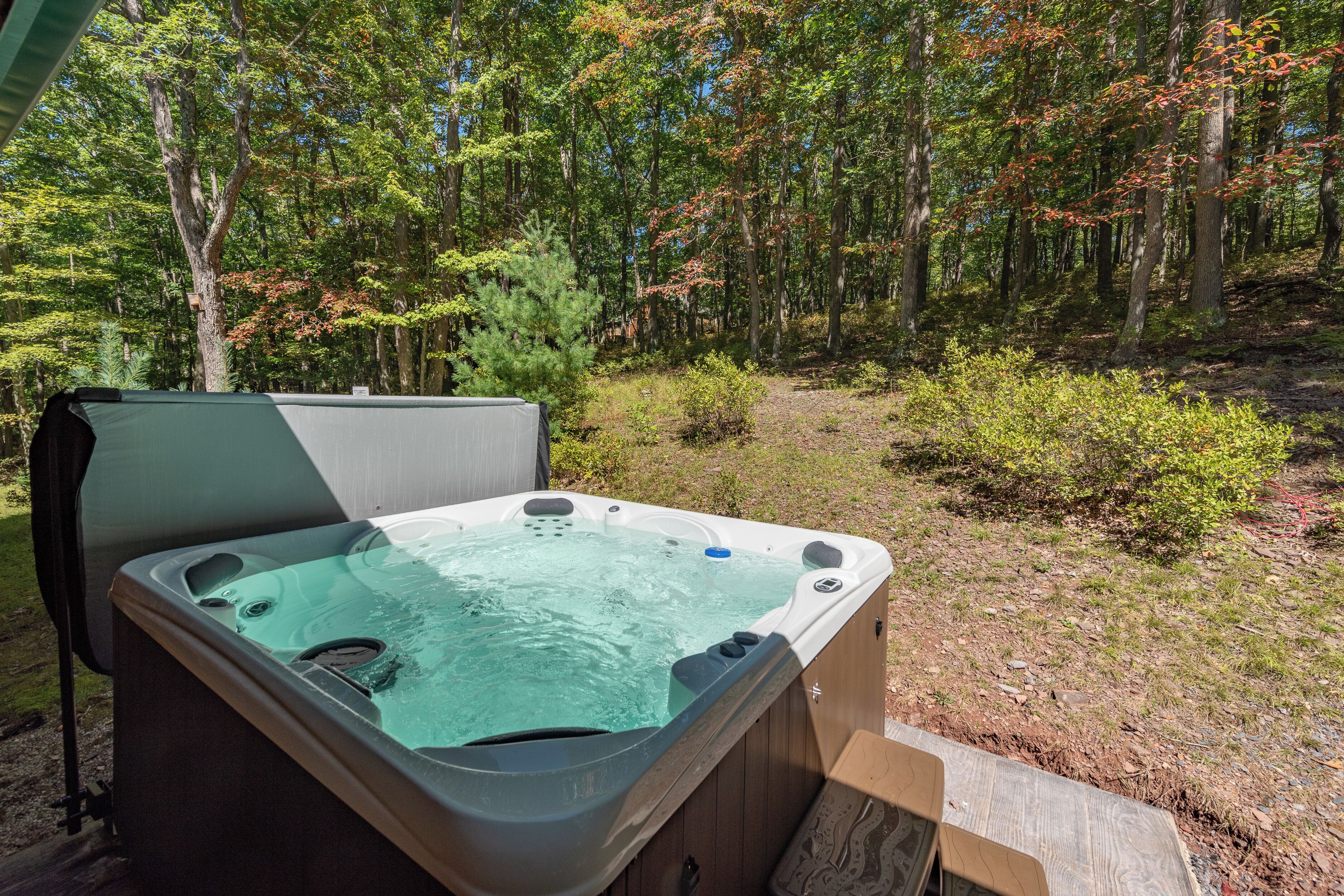 A hot tub in a wooded area with a wooden deck.