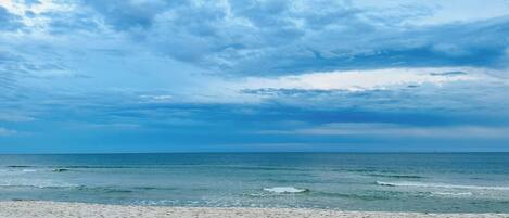 A beach with a sandy shore and a view of the ocean under a cloudy sky.