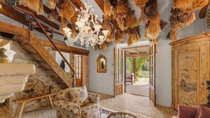 Ein rustikales Interieur mit einer Holztreppe, einem gemusterten Sessel, einem Glastisch und einem traditionellen Holzschrank.